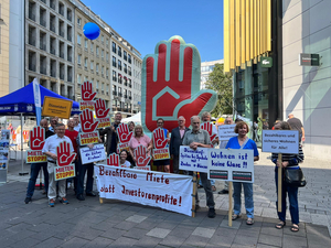 Die Fotos zeigen Personen, die sich an dem Aktionstag der Mietenstoppkampagne beteiligt haben. Die Menschen halten Transparente und Schilder hoch, auf denen z.B. „Düsseldorf braucht bezahlbarem Wohnraum“ oder „Wohnen ist keine Ware“ steht. Außerdem ist vielfach die sogenannte „Mietenstopp-Hand“ zu sehen. Es handelt sich um das Logo der Mietenstoppkampagne. Es handelt sich um eine erhobene Hand, die Einhalt gebieten soll.