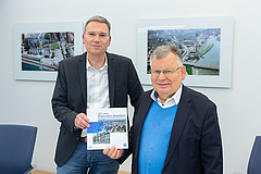 Geschäftsführer Claus Nesemann und Hans-Jochem Witzke stellen die Festschrift vor