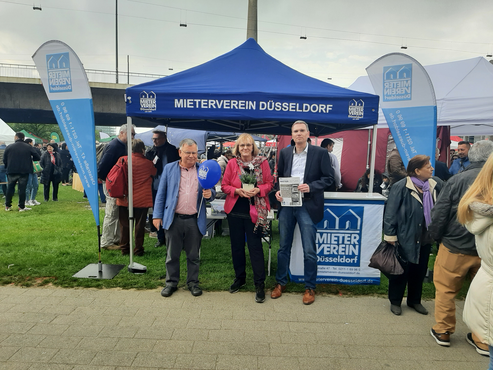 Die Fotos zeigen den Stand (Pavillon), den der Mieterverein Düsseldorf für den 1. Mai aufgebaut hat. Auf den Fotos sind Menschen zu sehen, die sich Informationen zum Mietrecht und zur Wohnungspolitik geben lassen. Außerdem sind auf den Fotos Hans-Jochem Witzke (1. Vorsitzender), Claus Nesemann(Geschäftsführer) und Sigrid Wolf (DGB Düsseldorf) zu sehen.