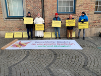 Das Foto zeigt fünf Mitglieder des Bündnisses, die vor dem Düsseldorfer Rathaus Schilder hochhalten. Auf den Schildern stehen z.B. Aufschriften wie „Düsseldorf braucht bezahlbare Wohnungen! Über 40.000 fehlen!“ oder „Düsseldorf Armut sofort bekämpfen“.