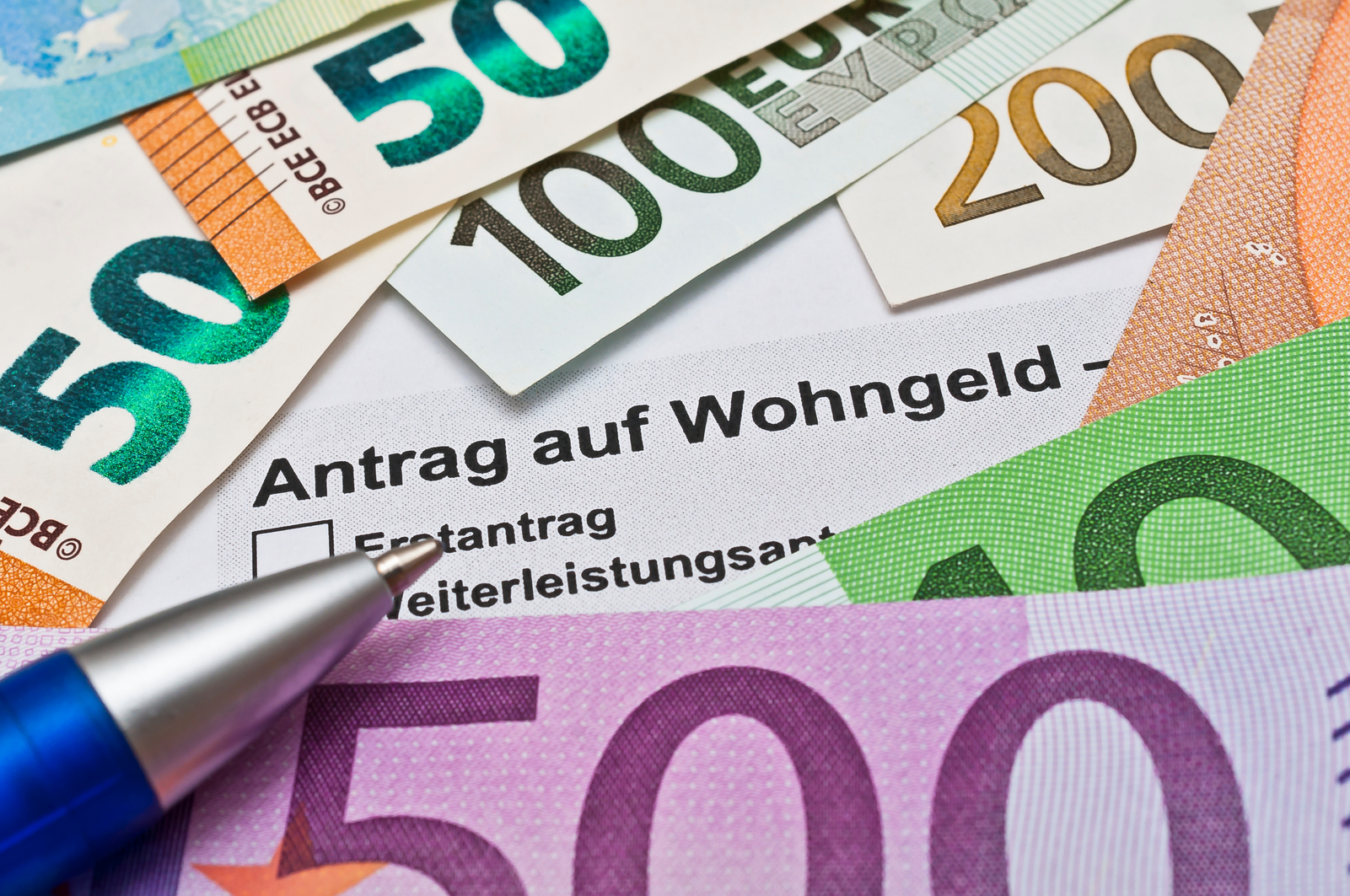 Foto von Geldscheinen und Kugelschreiber mit Antrag auf Wohngeld