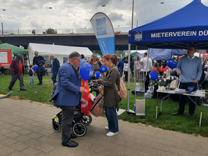Die Fotos zeigen den Stand (Pavillon), den der Mieterverein Düsseldorf für den 1. Mai aufgebaut hat. Auf den Fotos sind Menschen zu sehen, die sich Informationen zum Mietrecht und zur Wohnungspolitik geben lassen. Außerdem sind auf den Fotos Hans-Jochem Witzke (1. Vorsitzender), Claus Nesemann(Geschäftsführer) und Sigrid Wolf (DGB Düsseldorf) zu sehen.